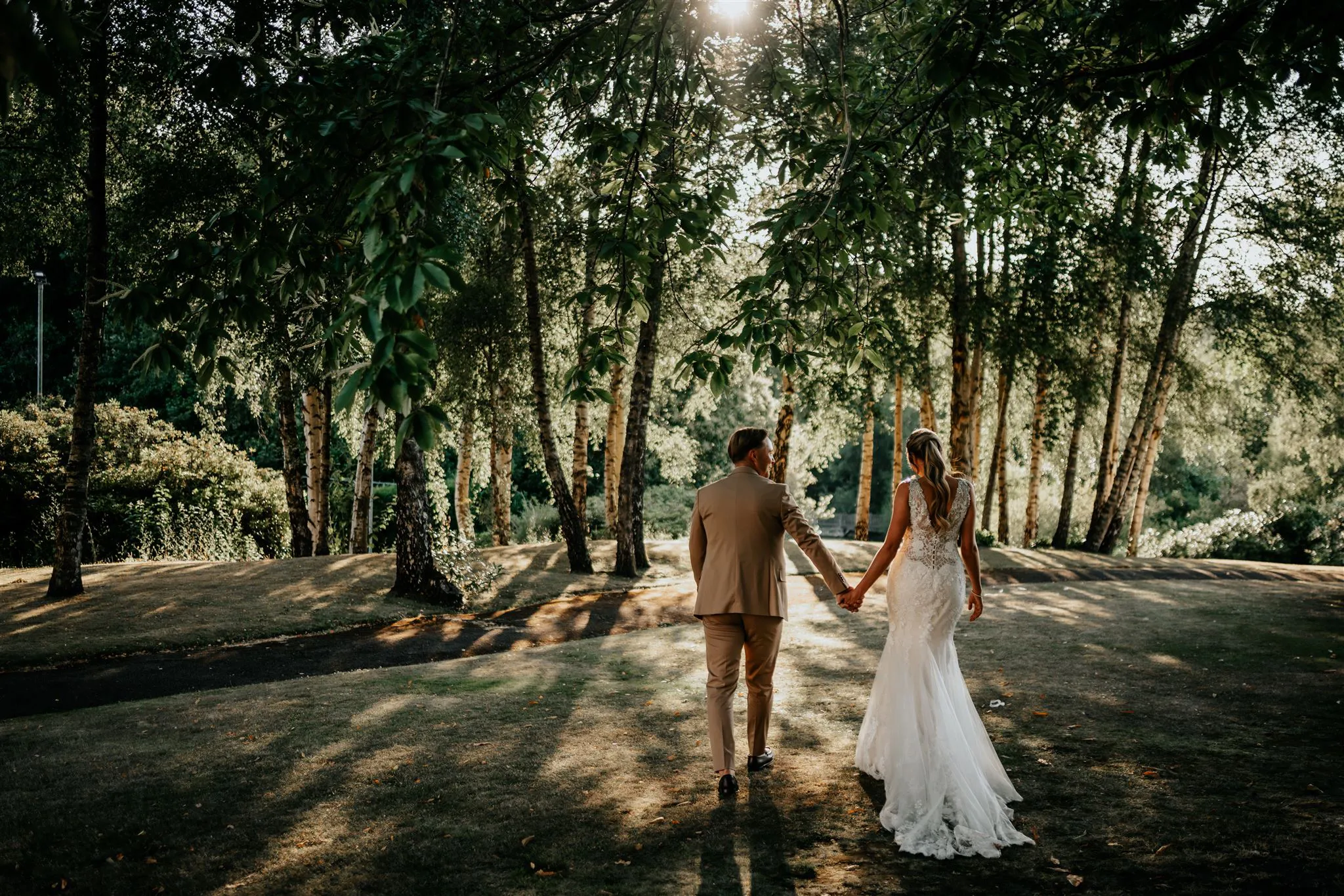 Bride and groom holding hands as they walk through the wooded grounds of The Spa Hotel, Tunbridge Wells