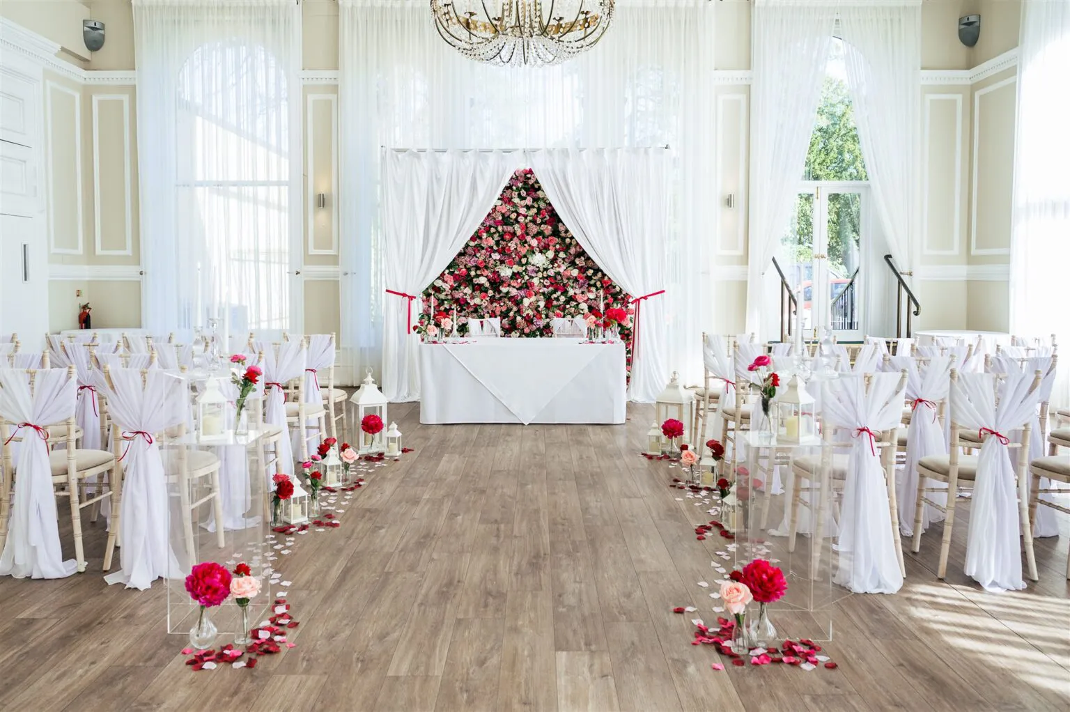 The Chandelier Suite set for a country house wedding ceremony with a pink rose flower wall and petal-lined aisle at The Spa Hotel, Tunbridge Wells